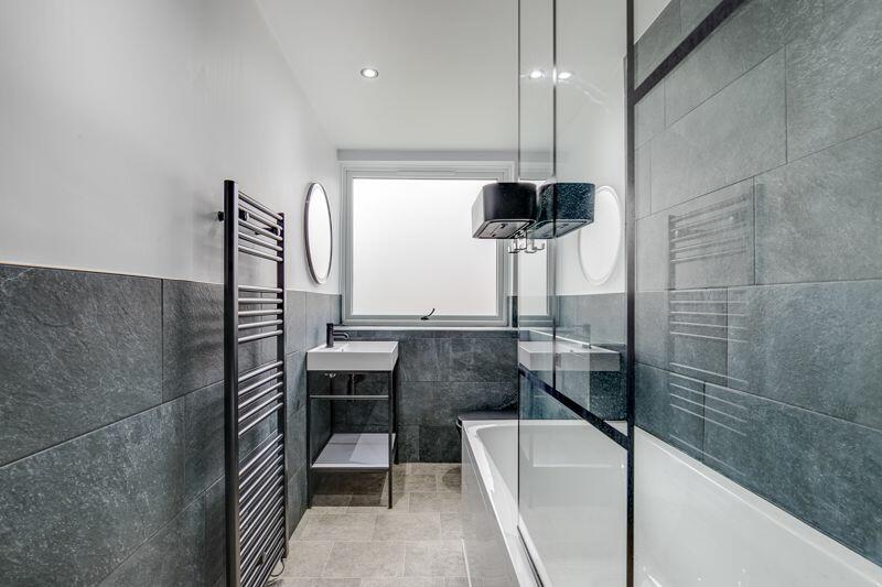Contemporary bathroom with dark slate tile, bath and glass screen