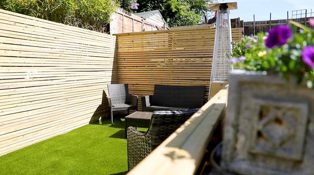 Decked garden at dusk with rattan furniture and patio heater