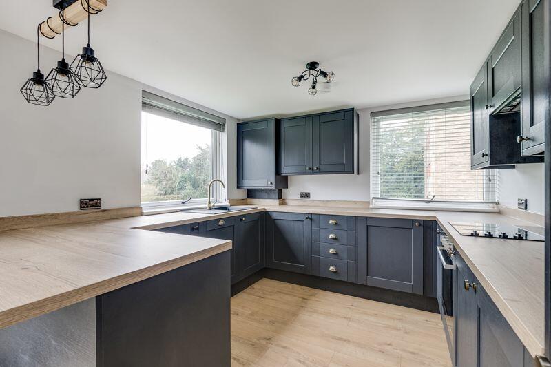 U-shaped navy shaker kitchen with oak worktops and brass tap