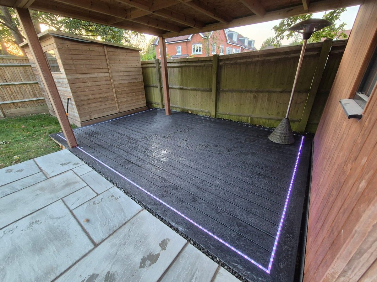 Charcoal composite deck at night with purple LED strip lighting inset around the perimeter